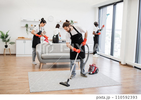Multinational group of cleaners cleans bright studio kitchen. Multinational group of cleaners cleans bright studio kitchen. 110592393
