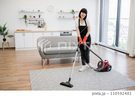 Professional female cleaner cleans modern apartment and looking at camera. Professional female cleaner cleans modern apartment and looking at camera. 110592481