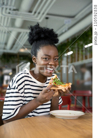 Pretty young dark-skinned woman eating pizza and feeling good 110592838