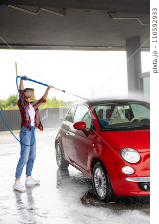 Young woman in checkered shirt washing a car 110592933