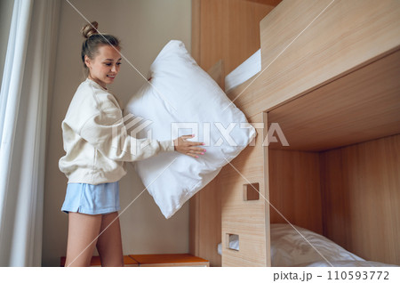 Beautiful woman putting on fresh bed linen in hotel room. Beautiful woman putting on fresh bed linen in hotel room. 110593772