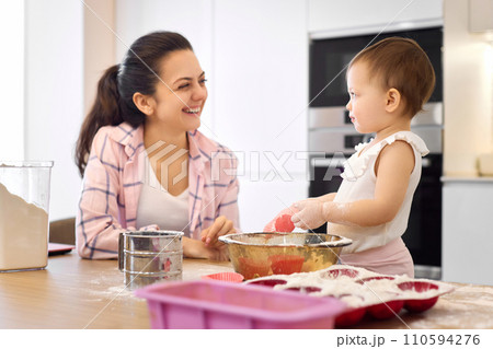mother and little baby girl preparing the dough in the kitchen, bake cookies. happy time together 110594276