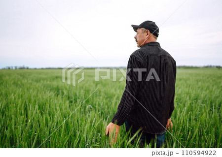 Farmer in a green wheat field. Agricultural growth and farming business concept. 110594922