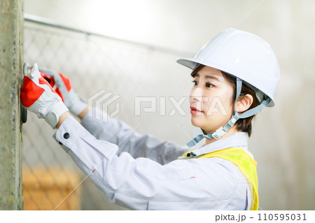 工事現場でメジャーを使う女性作業員 工事現場でメジャーを使う女性作業員 110595031
