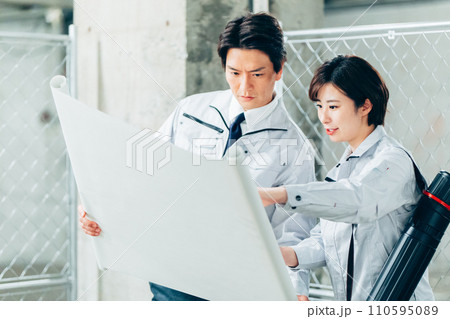 建築現場で図面を見ながらチェックする工事関係者 建築現場で図面を見ながらチェックする工事関係者 110595089