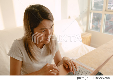 Woman in casual clothes working and typing with her computer laptop in her apartment in concept of work from home 110595200