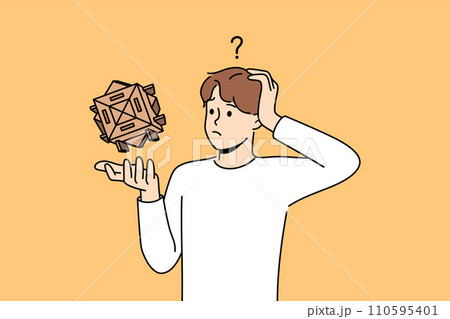 Confused man with wooden puzzle scratches head, wondering how to solve difficult problem 110595401