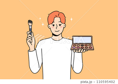 Non-binary man applies makeup and skin shadow, holding mirror and brush to apply powder 110595402