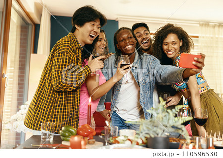 Smiling young friends taking selfie photo holding wine glasses on holiday dinner party at home 110596530