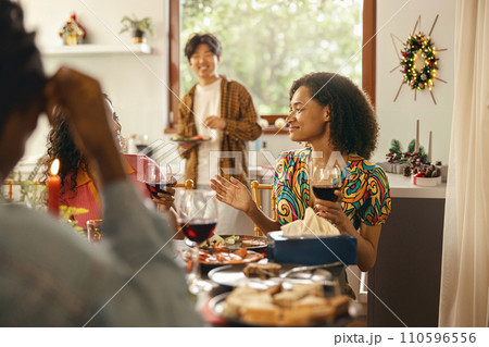 Happy friends enjoying in conversation and drinking wine during festive dinner at home party 110596556
