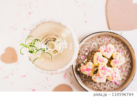 Close up of a cocktail with rosemary in a glass and candy hearts for Valentine's day top view 110596784