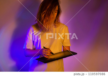 Modern tech slim girl in white shirt with digital tablet in neon bright light. Modern tech slim girl in white shirt with digital tablet in neon bright light. 110597086