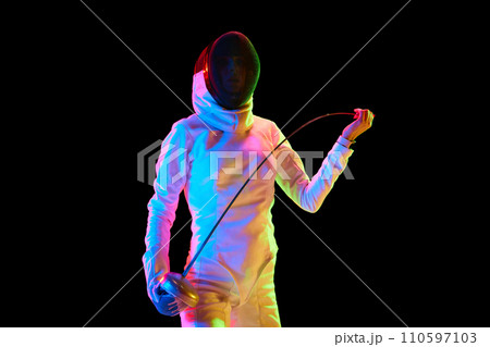 Portrait of female fencer, athlete in white uniform posing with sword over black background in neon light 110597103