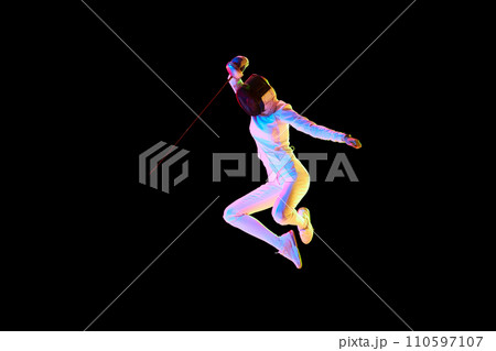 Self-defense skills. Although sportive, fencing skills can represent the broader theme of self-defense. Female athlete in motion, training over black background in neon. 110597107