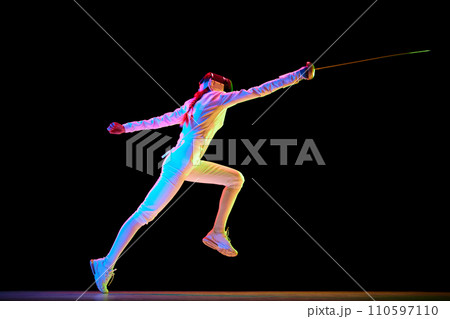 Action and motion. The dynamic motion of an athlete captured in a high-speed photograph. Female fencer training on black background in neon. 110597110