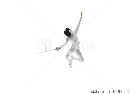 Strength and grace. Illustrating the combination of strength and grace necessary in the art of fencing. Female athlete, fencer in motion over white background 110597118