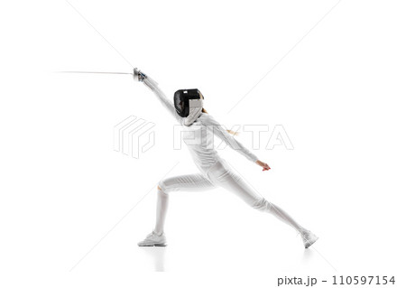 A fencer in full gear lunging with precision, isolated on a white background. Female athlete in motion, training with sword 110597154