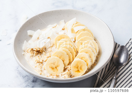Overnight oatmeal with banana and coconut chips. 110597686