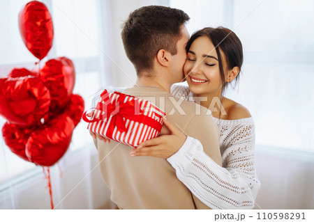 Valentine's Day concept. Lovers give each other gifts. Couple at home celebrating Valentine's Day. Valentine's Day concept. Lovers give each other gifts. Couple at home celebrating Valentine's Day. 110598291