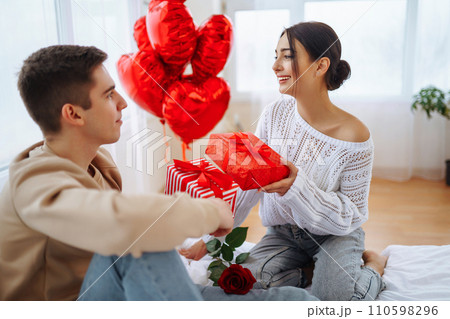 Valentine's Day concept. Lovers give each other gifts. Couple at home celebrating Valentine's Day. 110598296