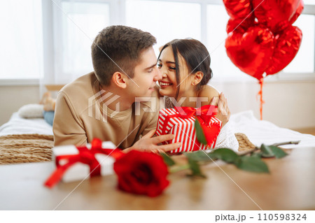 Valentine's Day concept. Lovers give each other gifts. Couple at home celebrating Valentine's Day. Valentine's Day concept. Lovers give each other gifts. Couple at home celebrating Valentine's Day. 110598324
