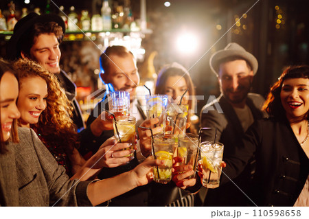 Cheering, drinking cocktails. Group of friends partying in nightclub and toasting drinks cocktails. Cheering, drinking cocktails. Group of friends partying in nightclub and toasting drinks cocktails. 110598658