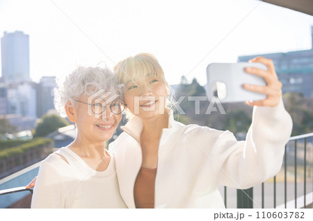 家族　スマホで自撮りをする若い女性とシニア女性 110603782