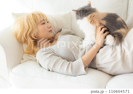 ソファーに寝転び猫を抱っこする日本人女性 ソファーに寝転び猫を抱っこする日本人女性 110604571