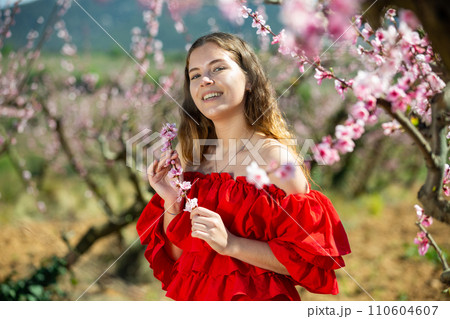 Portrait of happy girl in red dress in blooming spring garden 110604607