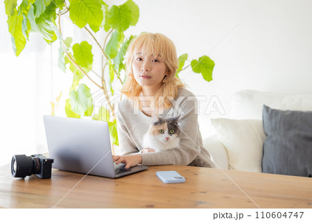 パソコンを見ている女性と猫 110604747