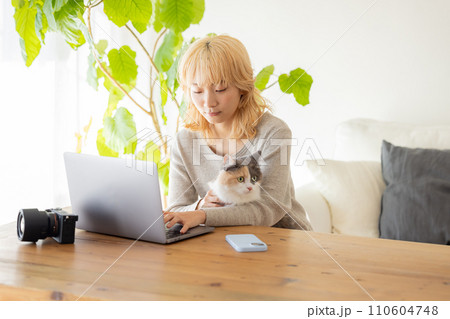 パソコンを見ている女性と猫 110604748