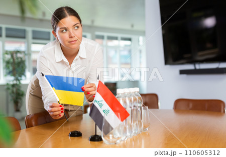Young lady sets miniatures flags of Iraq and Ukraine for international negotiations 110605312