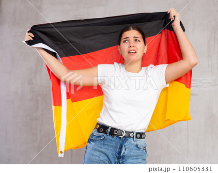 Unhappy female Germany team fan holding national flag Unhappy female Germany team fan holding national flag 110605331