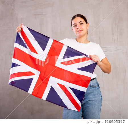 Smiling young woman holding United Kingdom flag Smiling young woman holding United Kingdom flag 110605347