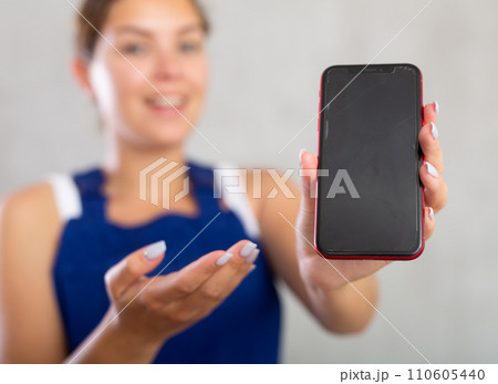 Young woman in work overalls posing with phone 110605440