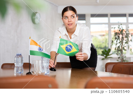 Young female attendant putting up flags for international negotiations between india and brazil 110605540