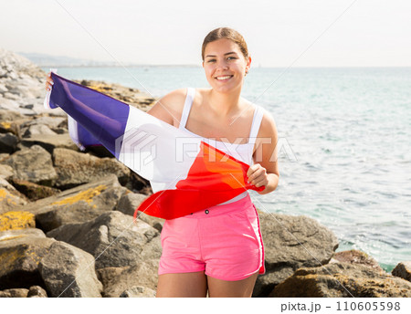 Young woman on coast posing with flag of France Young woman on coast posing with flag of France 110605598