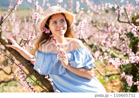 Beautiful blonde girl with long hair in a pink dress in blooming garden. 110605732