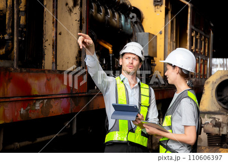 Young caucasian engineer man and woman checking train with tablet in station. Young caucasian engineer man and woman checking train with tablet in station. 110606397