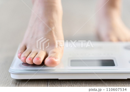 体重計に乗る女性の足元 体重計に乗る女性の足元 110607534