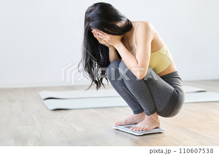 体重計に乗って落ち込むアジア人女性 体重計に乗って落ち込むアジア人女性 110607538