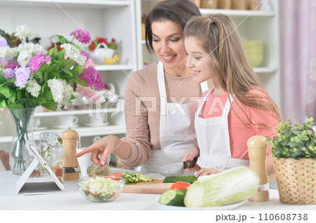 Smiling mother and daughter cooking together at kitchen 110608738