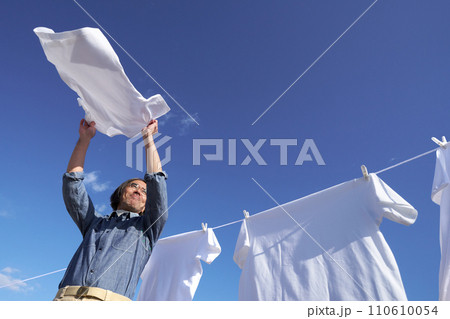 青空のもとで洗濯物のシャツを干すミドル男性 青空のもとで洗濯物のシャツを干すミドル男性 110610054