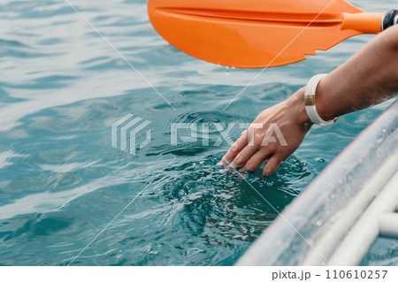 Woman in kayak back view. Happy young woman with long hair floating in transparent kayak on the crystal clear sea. Summer holiday vacation and cheerful female people relaxing having fun on the boat Woman in kayak back view. Happy young woman with long hair floating in transparent kayak on the crystal clear sea. Summer holiday vacation and cheerful female people relaxing having fun on the boat 110610257