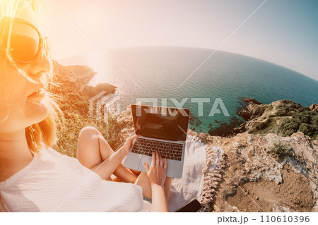Woman sea laptop. Business woman working on laptop by sea at sunset. Close up on hands of pretty lady typing on computer outdoors summer day. Freelance, digital nomad, travel and holidays concept. 110610396
