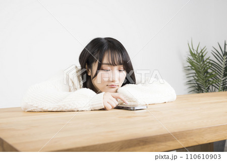 頬杖をつきスマホを見ている若い女性 頬杖をつきスマホを見ている若い女性 110610903