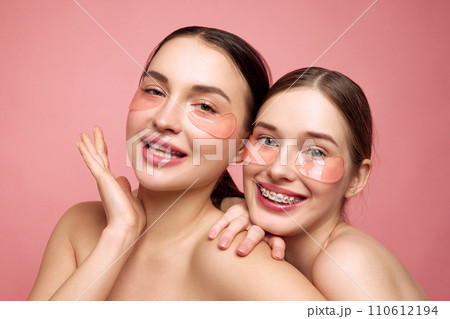 Hydrated harmony. Young girls embrace their makeup-free charm, coming together to care under-eye area with moisturized, hyaluronic patches Hydrated harmony. Young girls embrace their makeup-free charm, coming together to care under-eye area with moisturized, hyaluronic patches 110612194