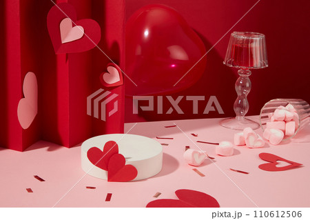 Round podium in white color displayed with red balloon, many heart-shaped marshmallows. Glamour minimal pedestal for beauty, cosmetic product presentation 110612506