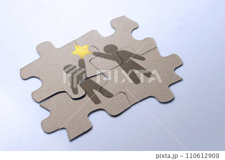 Closeup view of a jigsaw puzzle with two human figures holding a star Closeup view of a jigsaw puzzle with two human figures holding a star 110612908