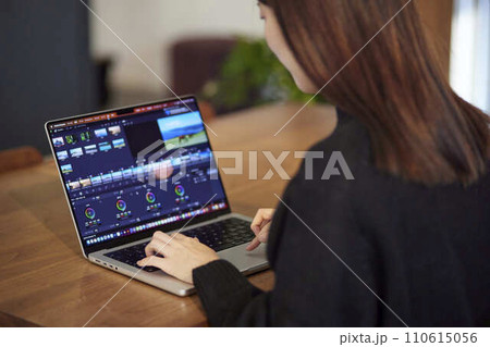 ノートパソコンにて動画編集を行うクリエイターの日本人女性 110615056